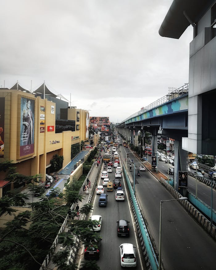 A vibrant urban scene in Kochi, India, featuring a busy street with cars and a prominent shopping mall.